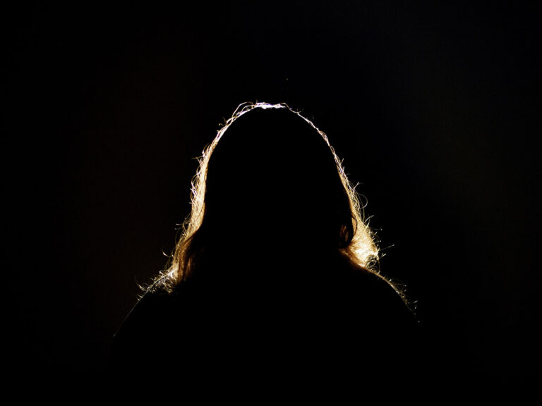 A person with long hair standing in the dark